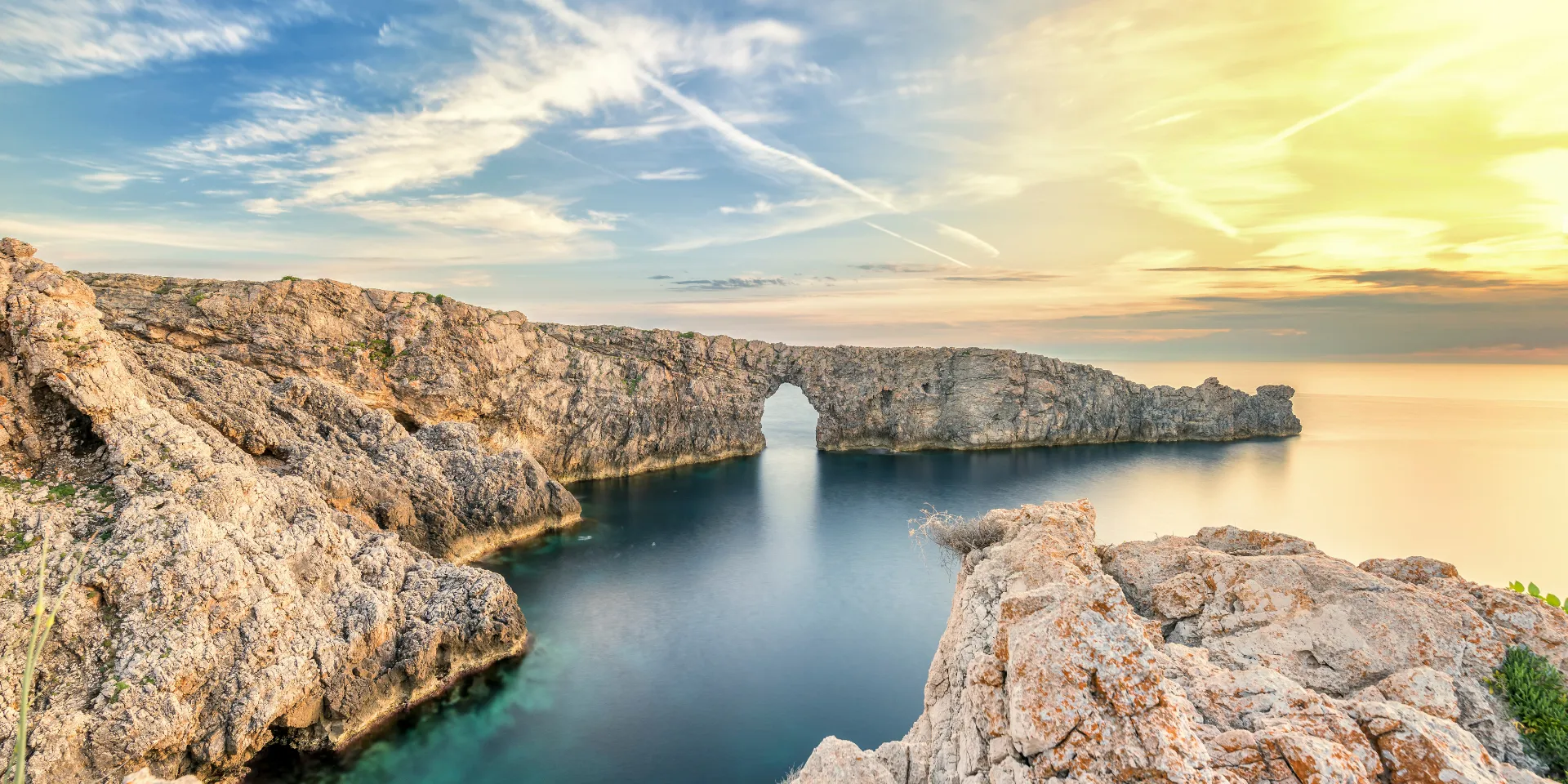 Felsbogen an der Küste von Menorca mit Blick auf das Meer.