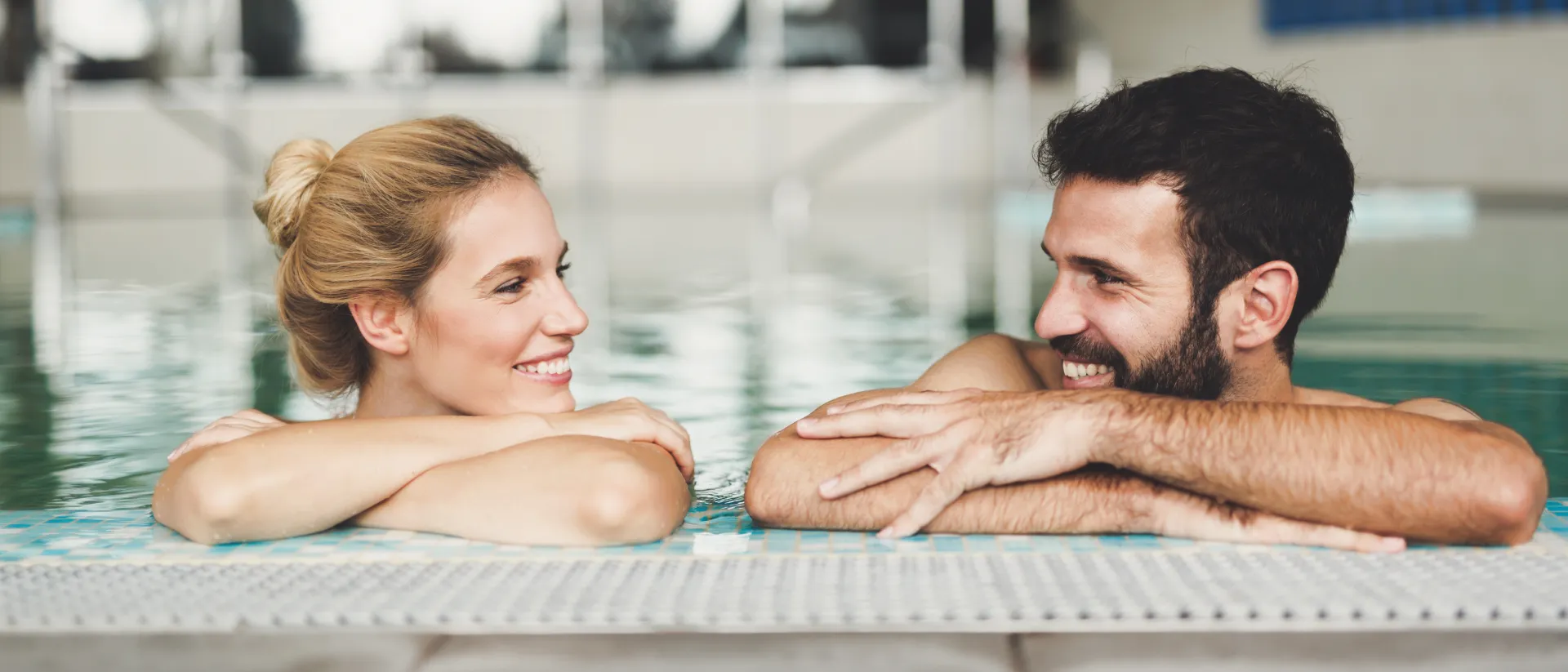 Zwei Personen im Schwimmbecken am Beckenrand.