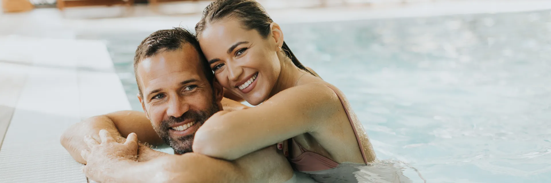 Zwei Personen im Schwimmbecken am Beckenrand.