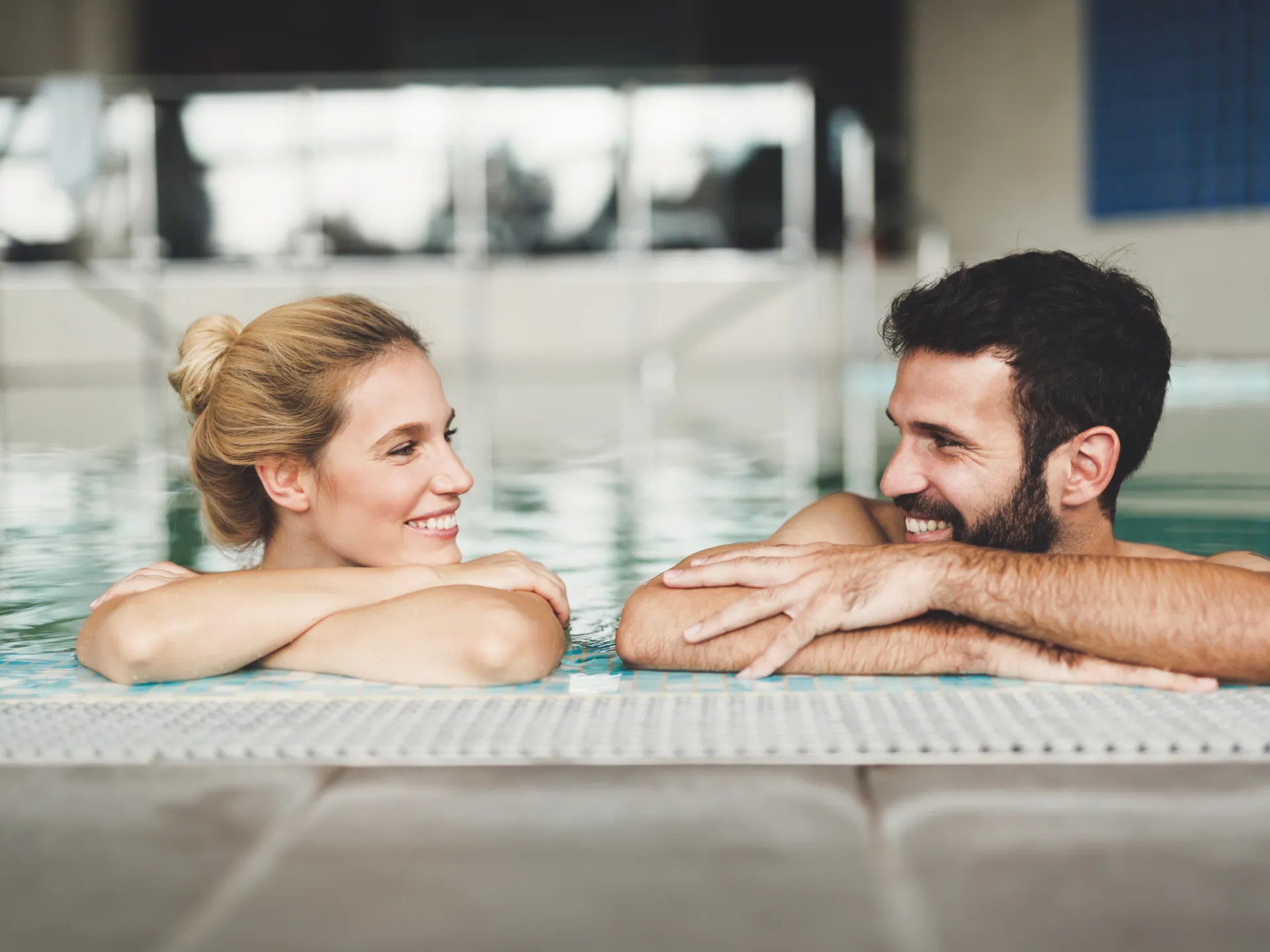 Zwei Personen im Schwimmbecken am Beckenrand.
