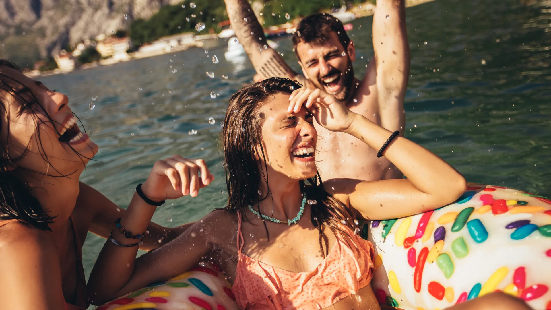 Lachende Freunde im Wasser am Strand