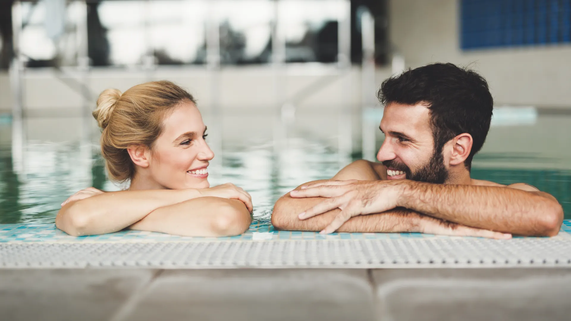 Zwei Personen im Schwimmbecken am Beckenrand.