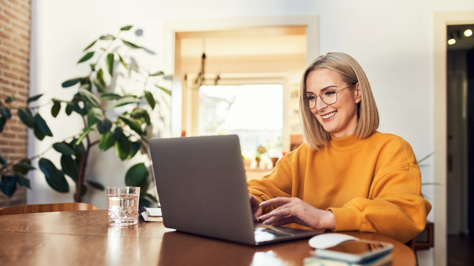 Eine Frau sitzt vor einem Laptop und sucht ihre nächste Reise.