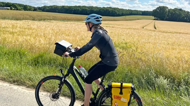 Radfahrer am Radweg mit Kornfeldern im Hintergrund